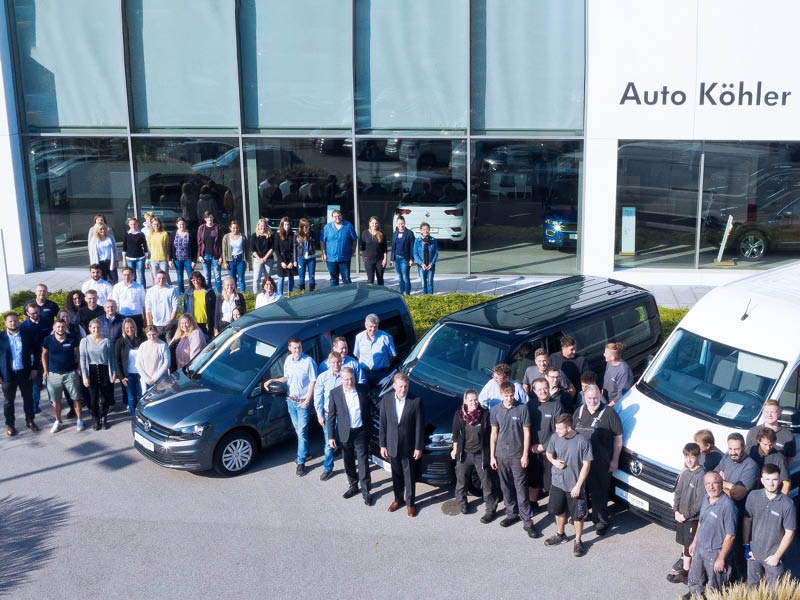 Alle Mitarbeiter stehen mit VW Nutzfahrzeugen vor dem Firmengebäude