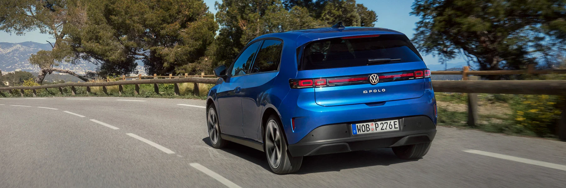 Zu sehen ist ein blauer VW ID Polo von hinten auf der Landstraße
